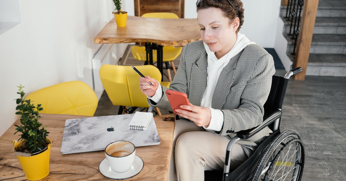 Does stun from artillery disable crew perks? - High angle of focused female in wheelchair browsing cellphone at table with netbook and cup of latte