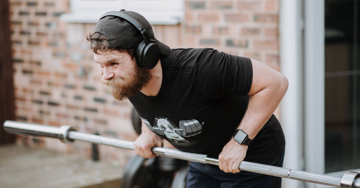 Does the HP of a Pokemon change after EV training it? - Brutal male with headphones pulling massive metal barbell on blurred background of brick house