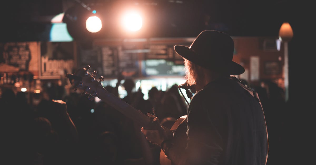 Does the In Rhythm talent stack with itself? - Back view of anonymous male artist playing acoustic guitar and singing song on stage during concert in dark club