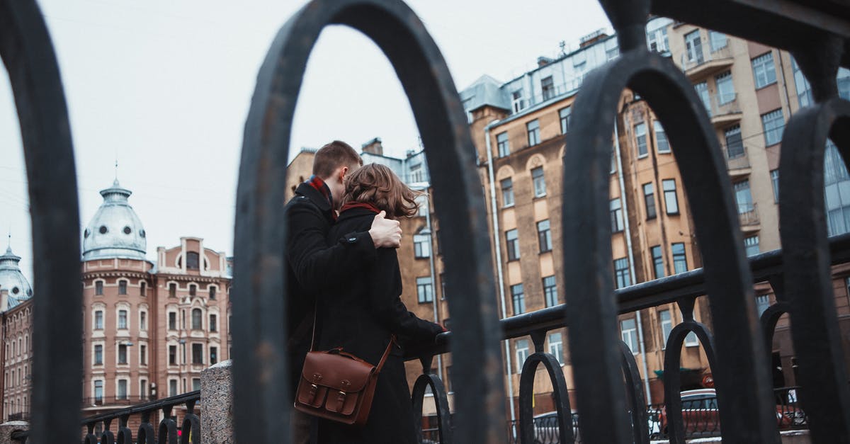 Does the weather affect the noise I make? - From below of anonymous female and male in warm clothes standing near railing together and hugging in cold weather