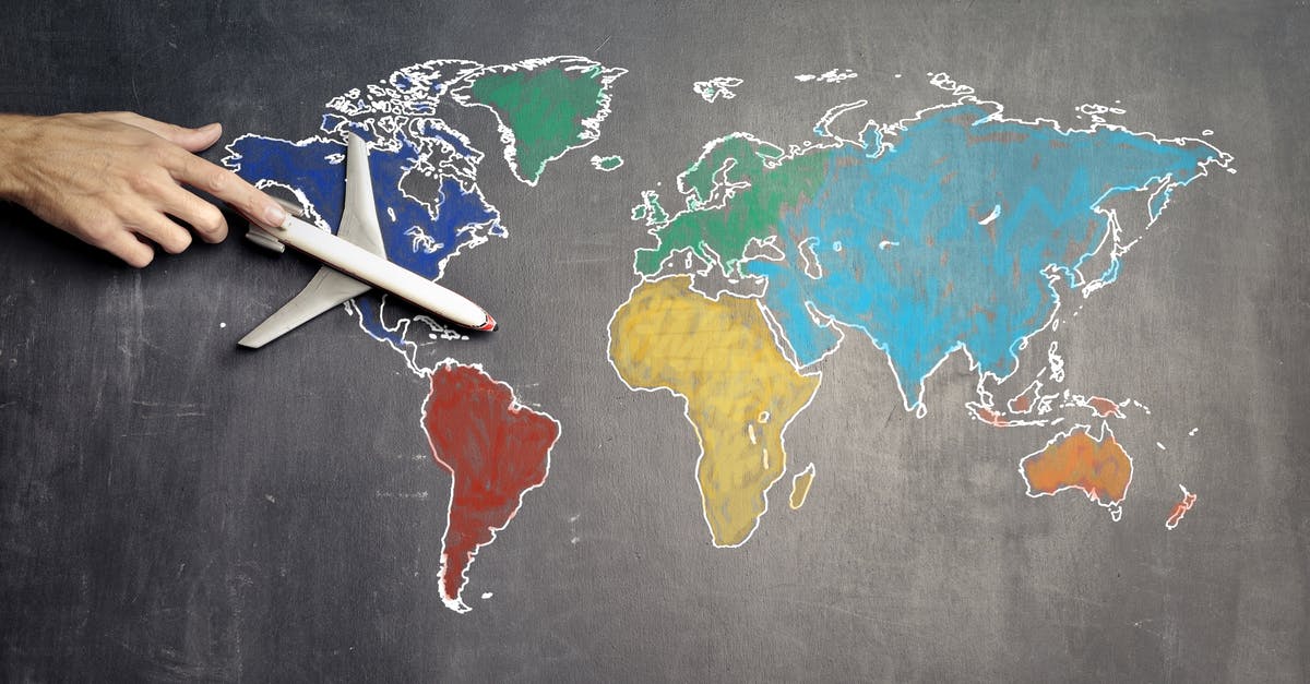 Does the world simulate while underground? - Top view of crop anonymous person holding toy airplane on colorful world map drawn on chalkboard