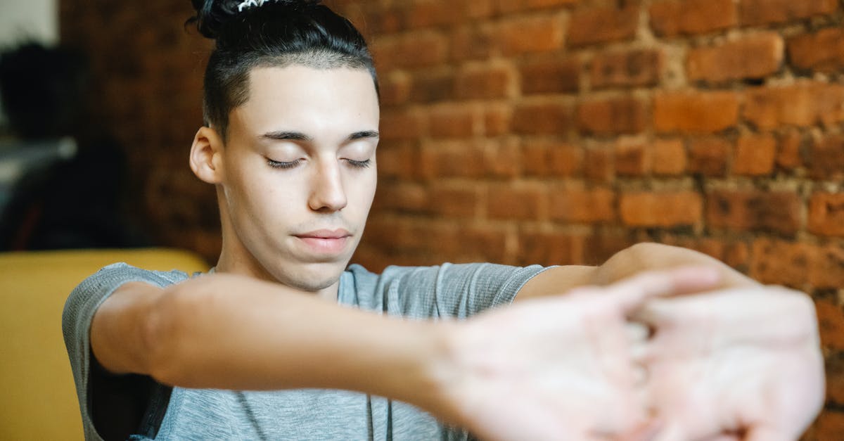 Don't have the needed software to perform this action? - Young male athlete with creative hairstyle cracking knuckles and closing eyes while doing exercise