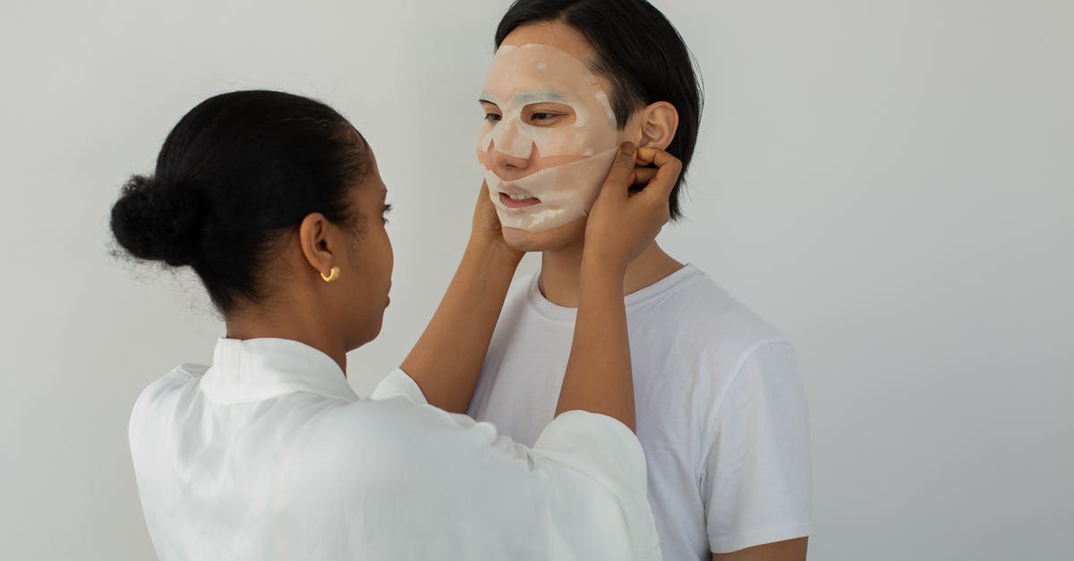 Don't Starve Together - how to find each other - African American female beautician applying moisturizing mask on face of young ethnic man while looking at each other on light background