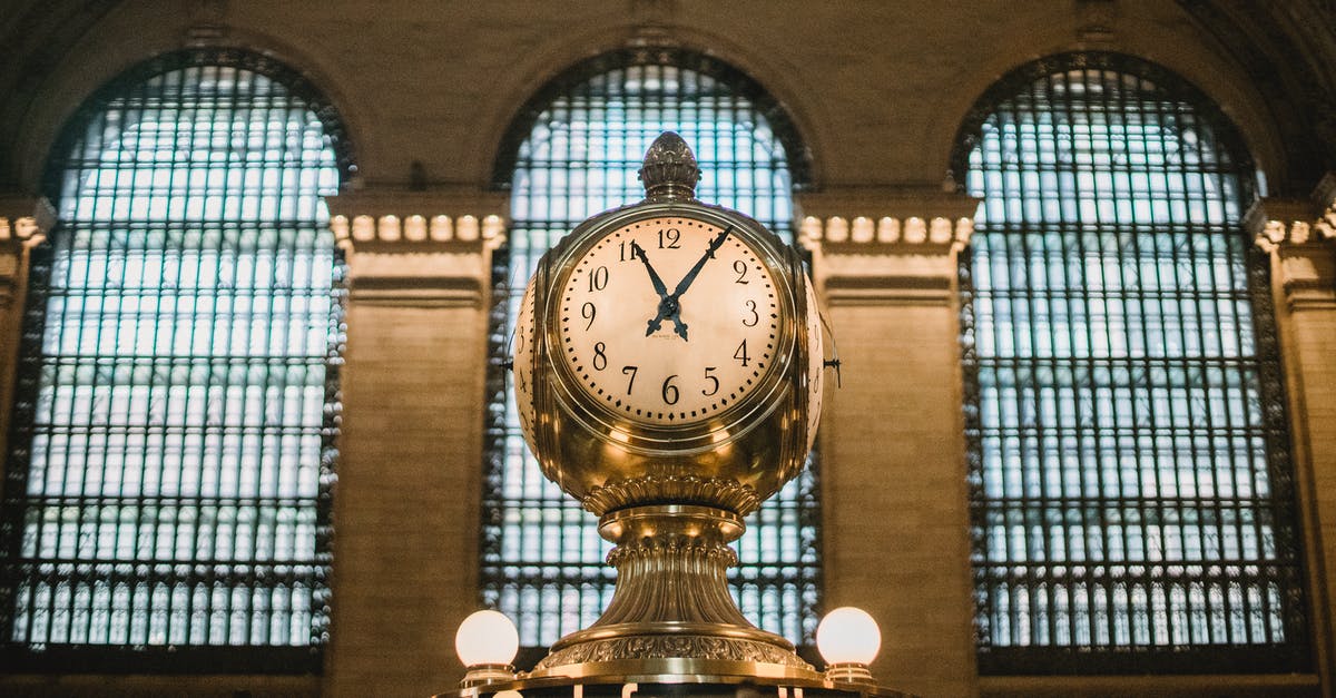 Dragon age inquisition; the time to complete mission glitched - From below of aged retro golden clock placed atop information booth of historic Grand Central Terminal with arched windows