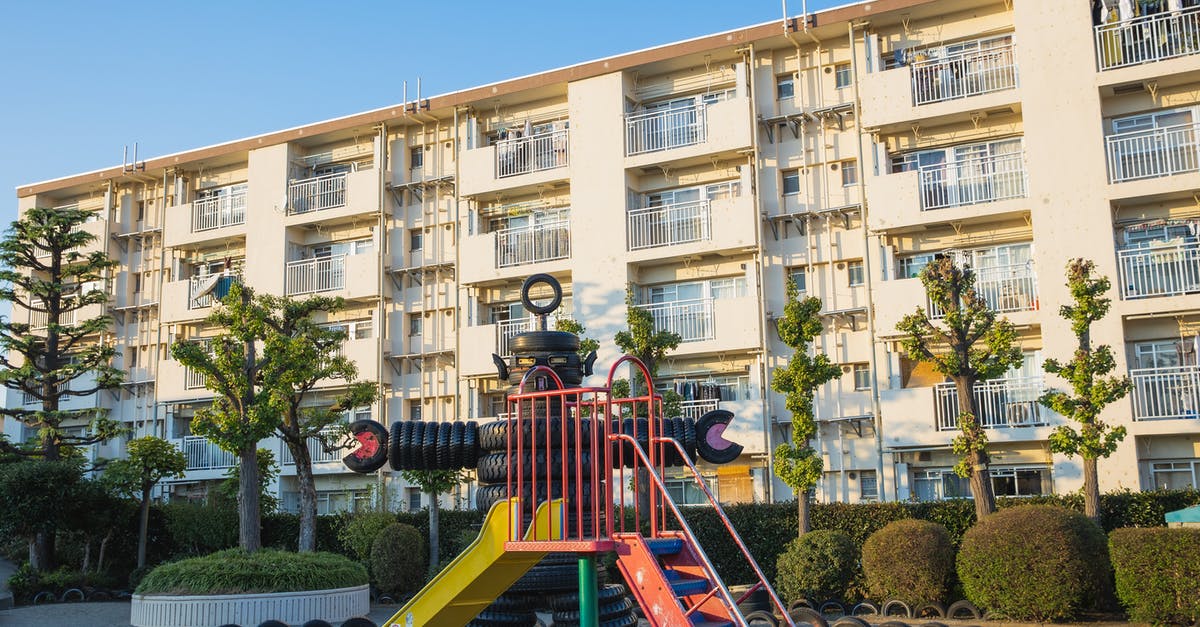 Efficient use of Construction Robots - Playground in suburb yard with metal slide and huge robot made of pile of old rubber tyres