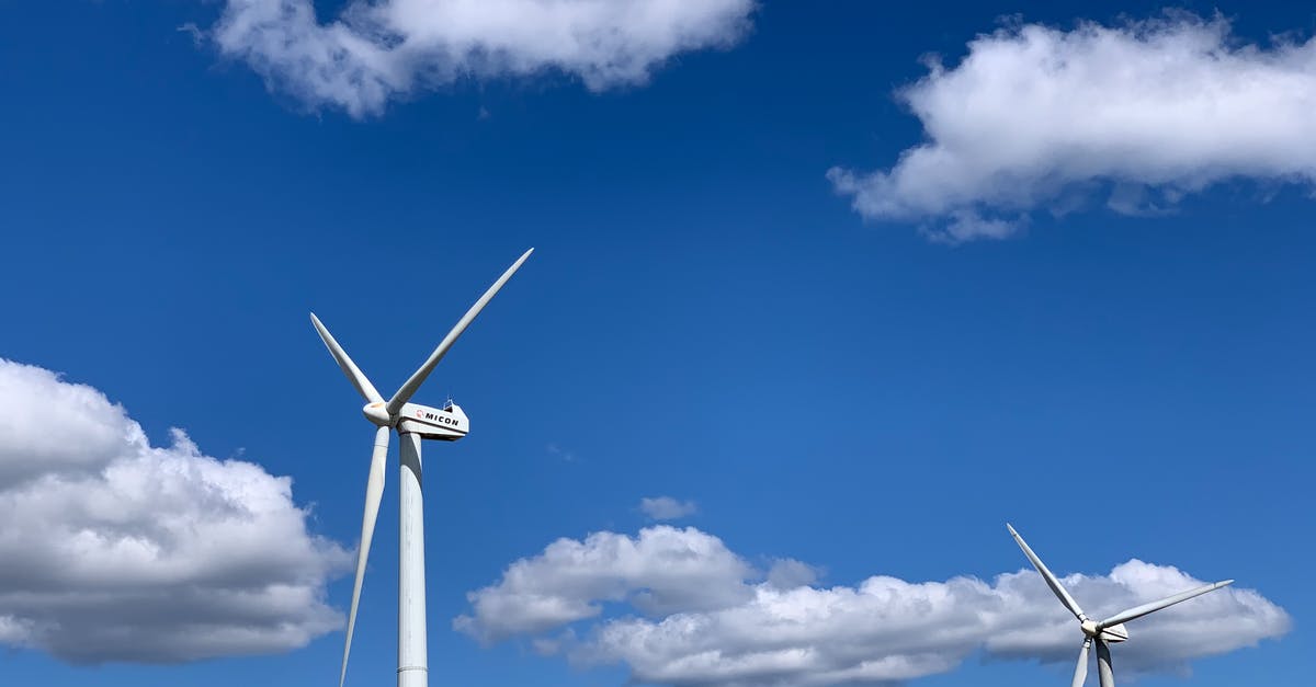 Efficient use of Construction Robots - Low angle of white modern windmill turbines generating energy against cloudy blue sky on sunny day