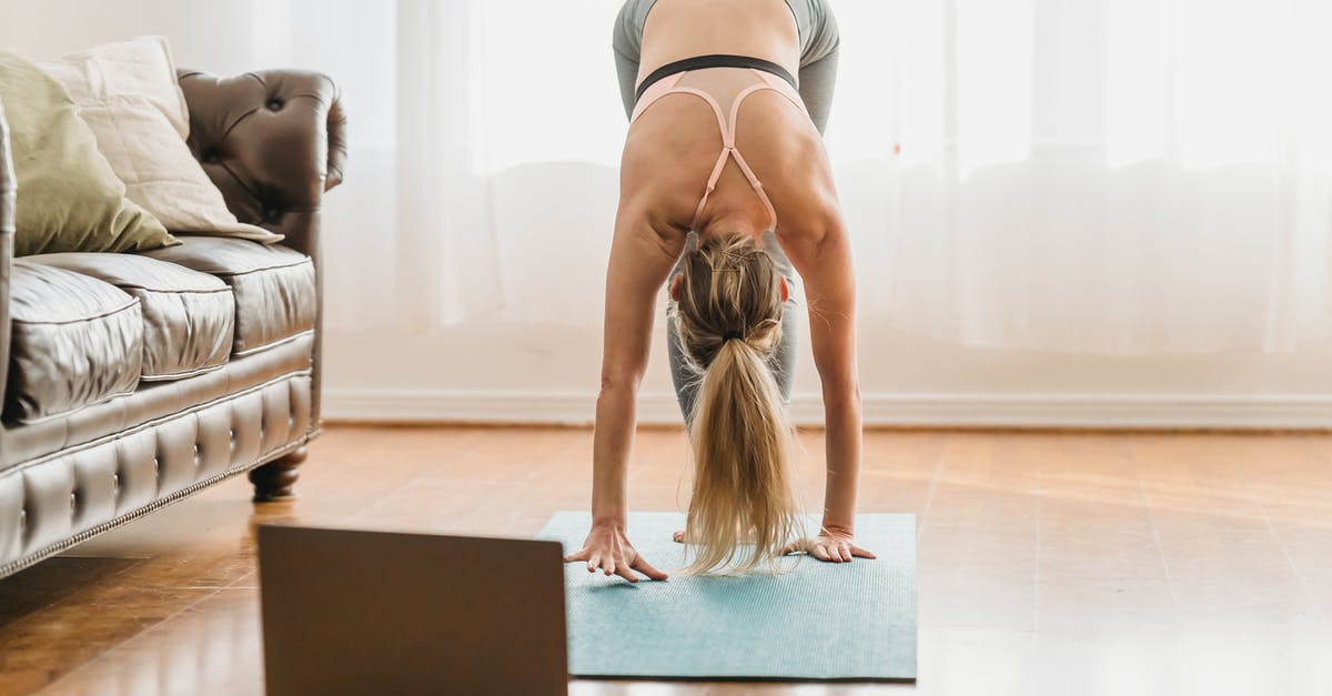 Entering the Training Complex in Valorant Tutorial - Full body of unrecognizable female in activewear performing standing forward bend asana while standing on mat near laptop during online yoga lesson at home