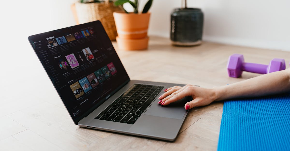 Entering the Training Complex in Valorant Tutorial - Hand of anonymous female on touchpad of laptop while surfing internet lying on mat at home during workout