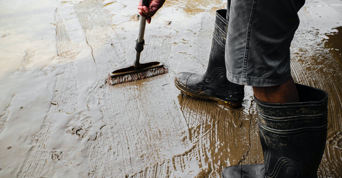 eShop version of Metroid Prime Trilogy freezes on WiiU - Side view of crop anonymous male worker in gumboots with brush priming cement floor at work