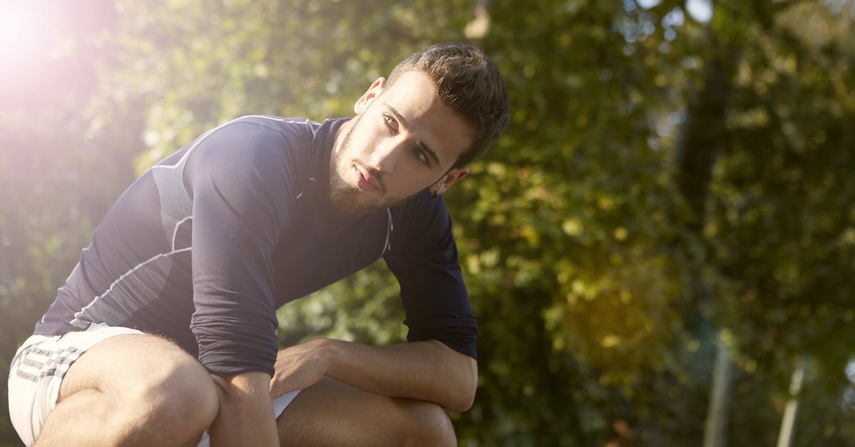 Fall Guys on Low Spec [duplicate] - Concentrated sportsman in activewear crouching in park while resting during fitness training and looking away