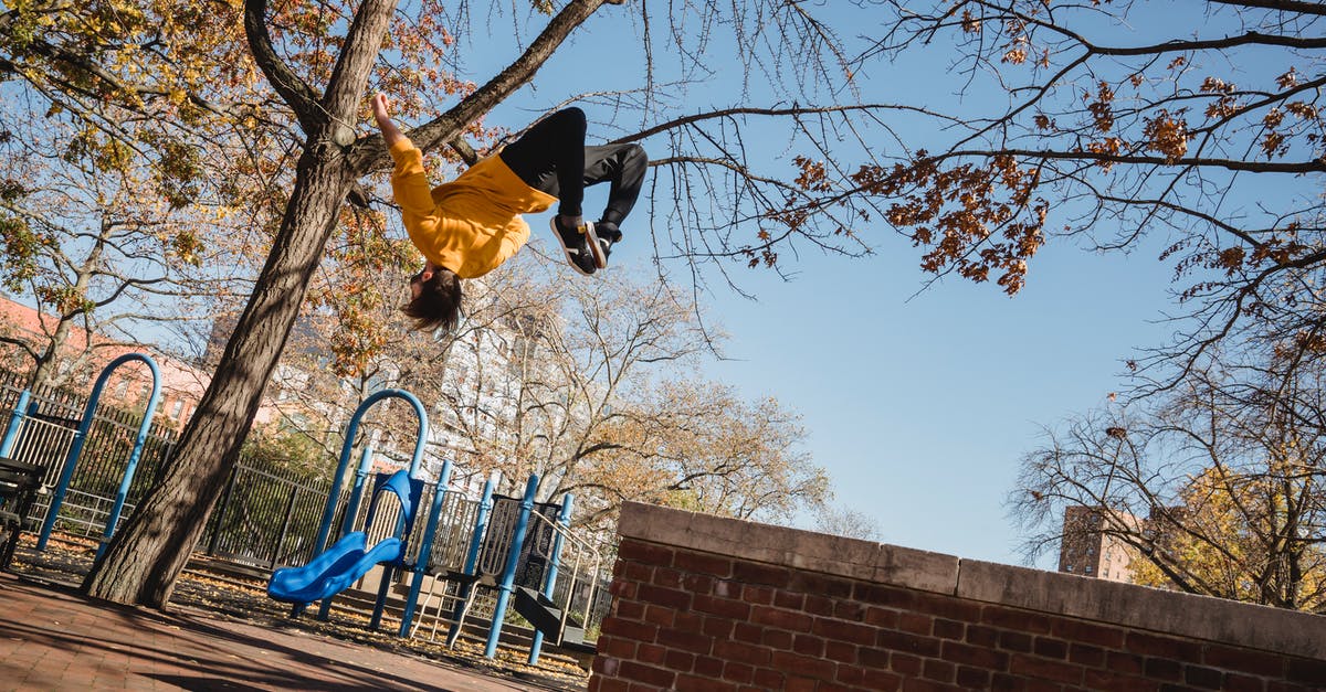 Fall Guys on Low Spec [duplicate] - From below full length of faceless young male wearing casual clothes and jumping from fence while doing parkour stunts in city street in autumn day