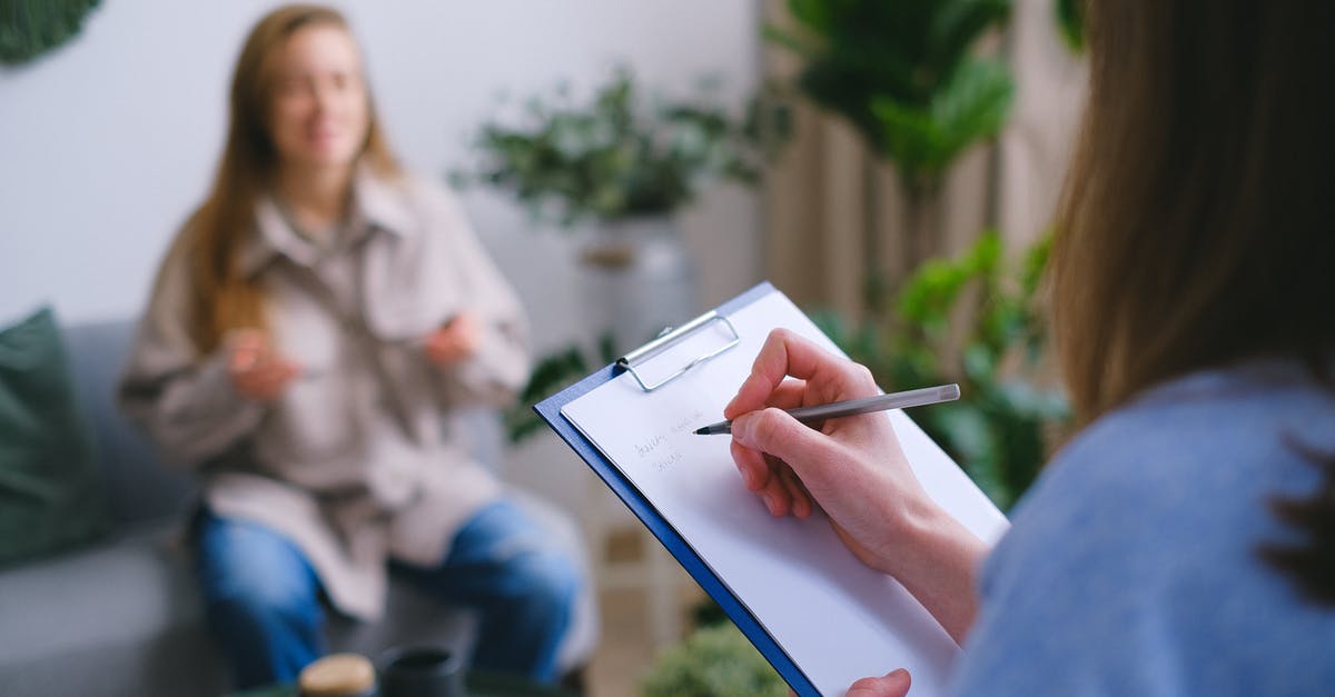 Gamecube disc issue - Unrecognizable professional female psychologist writing on clipboard while sitting against client on blurred background during psychotherapy session in light office