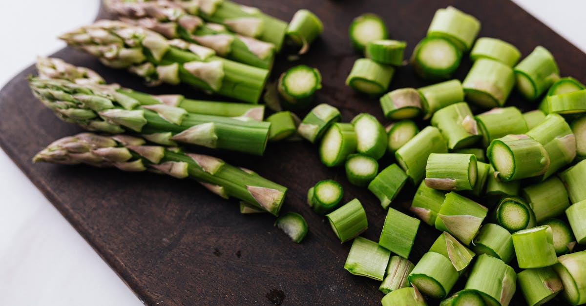 Get half-life CD key from Steam - Closeup of green chopped stems of asparagus placed on wooden cutting board on white surface