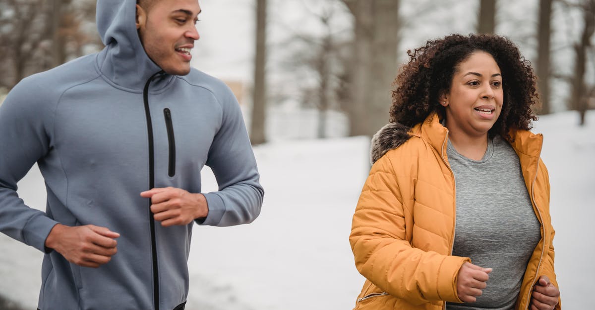 Help me run the numbers on a perfect IV ditto - Positive African American male personal instructor running with overweight female in park in winter day