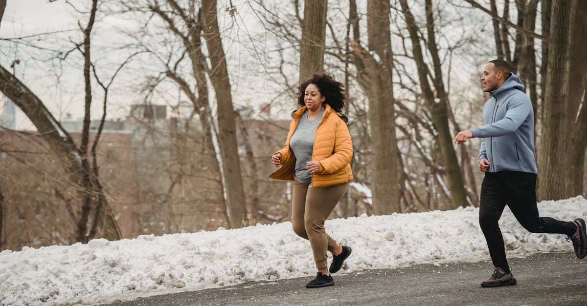 Help me run the numbers on a perfect IV ditto - Full body of plus size African American female running with personal instructor on asphalt road during winter training on street