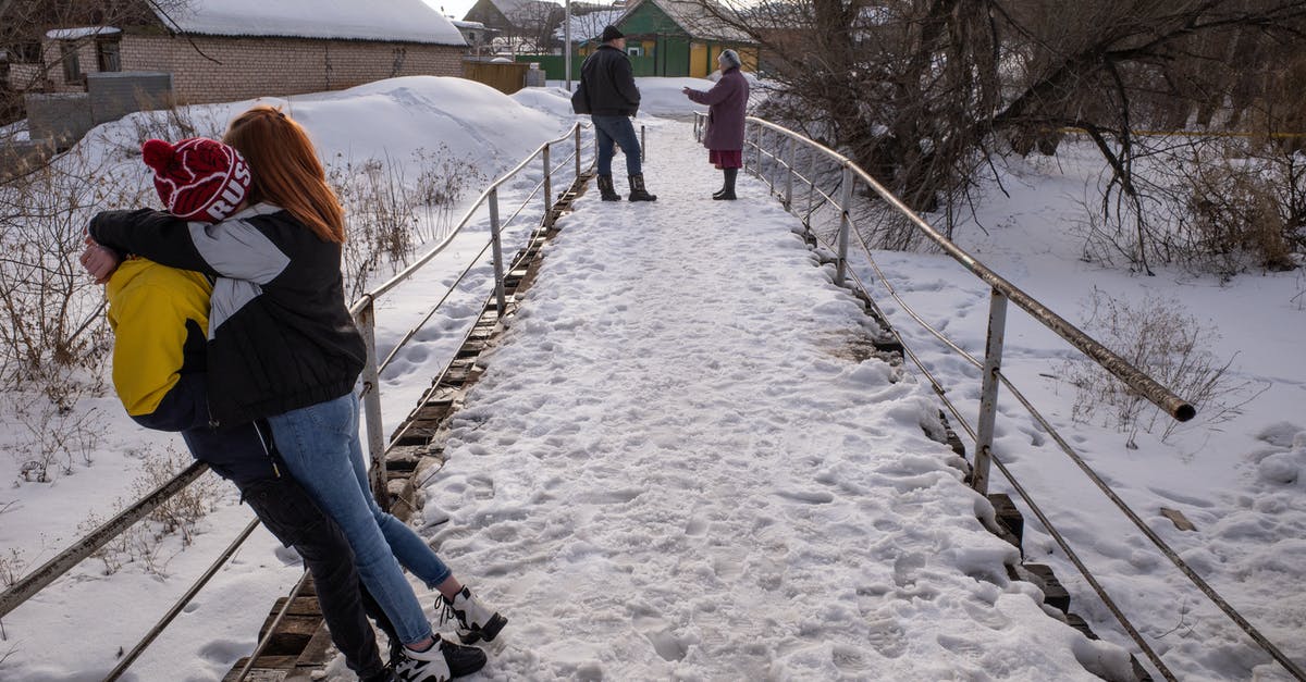 Homeless people, but multiple vacant houses - Couple Hugging on Snow Covered Bridge 