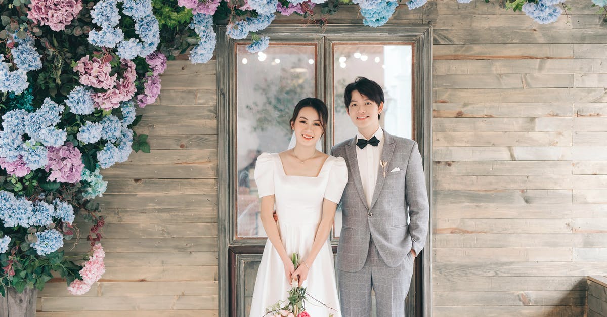 Homeless people, but multiple vacant houses - Newlyweds Standing in front of Wooden House under Hydrangea Garland