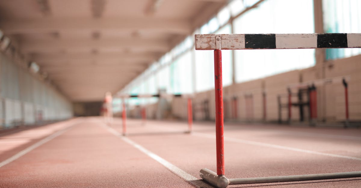 How are drops treated on (fast) travel to a different area? - Hurdle painted in white black and red colors placed on empty rubber running track in soft focus