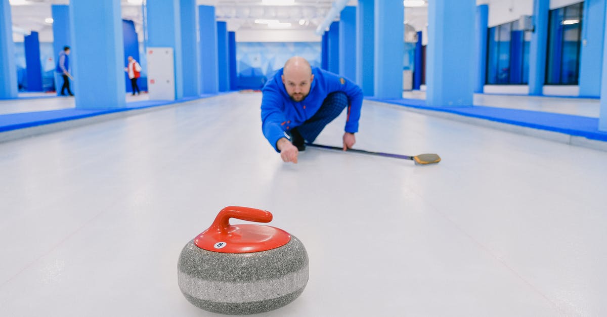 How can I boost mouse cursor speed in game menu? - Focused sportsman in blue activewear standing on knee with broom stick and looking at sliding stone during curling training on ice rink