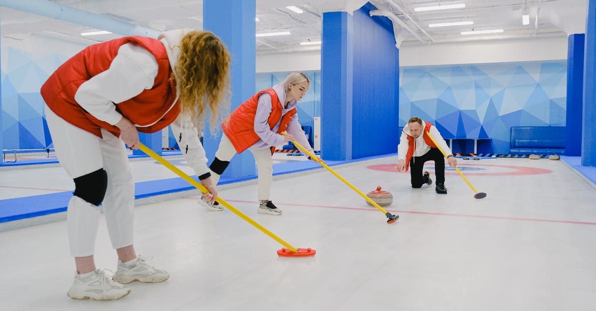 How can I boost mouse cursor speed in game menu? - Full body of sportsman throwing curling stone near sportswomen in activewear sweeping ice sheet with special brooms while playing game