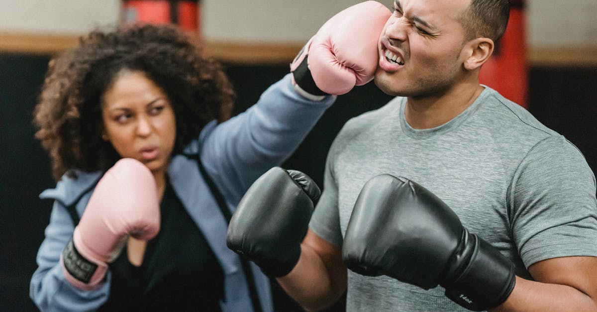 How can I tell when I make an offhand punch attack? - Determined young African American female fighter in activewear and boxing gloves punching in face of ethnic male coach during training in ring