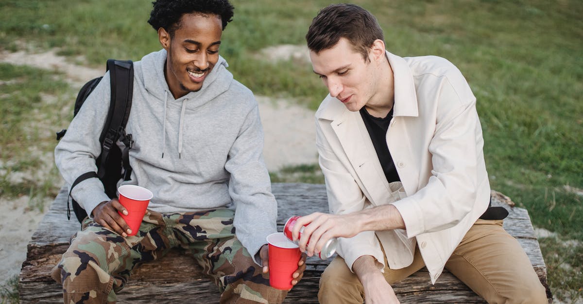 How can we kill the deerclops in don't starve together? - High angle of male pouring carbonated drink from tin can to smiling black friend sitting with red cup