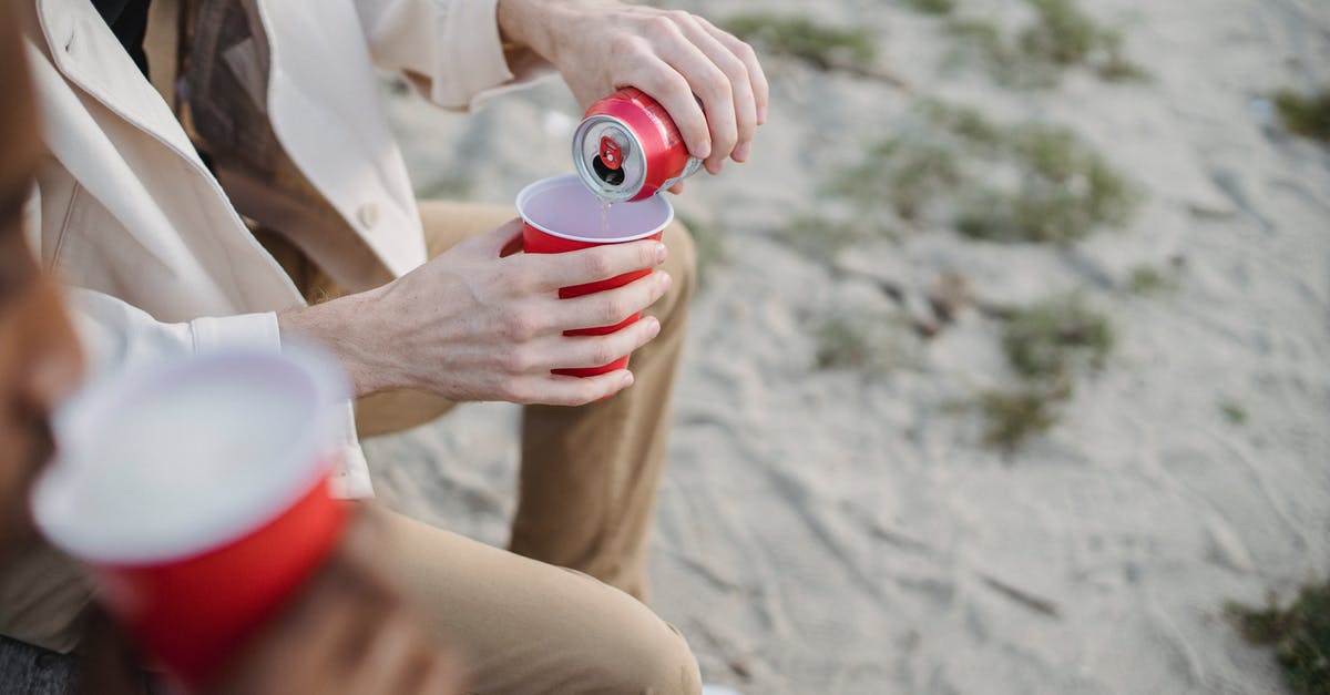 How can we kill the deerclops in don't starve together? - High angle of crop anonymous male pouring refreshing drink into red cup while sitting on sandy shore with black friend