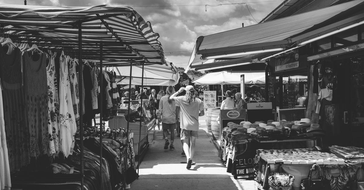 How do (construction) robots select the Roboport where they recharge? - Black and white of crowd of people strolling in market with different clothes and goods in daytime