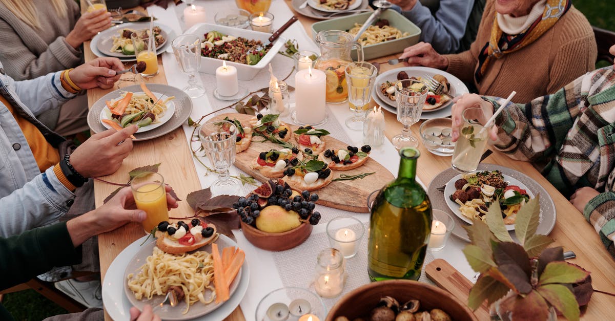 How do extra party members affect fullness when ordering food? - From above crop people enjoying festive dinner with snacks at garden table with candles burning