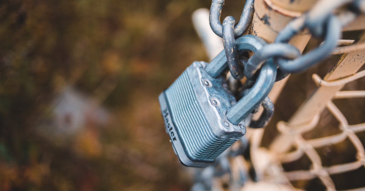 How do I attach ragdolls to other objects? - From above of small metal lock on chain attached to shabby net mesh fence in autumn park