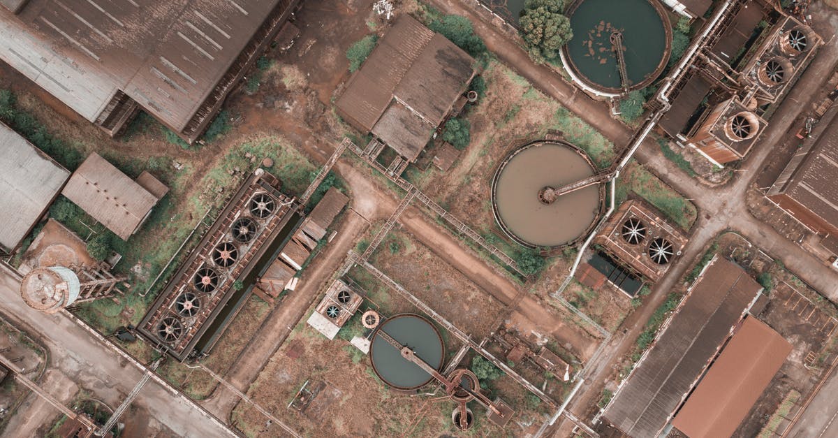 How do I automate power in 2021? - Drone view of shabby factory with round settling tanks with mechanical means removing solids in water treatment plant