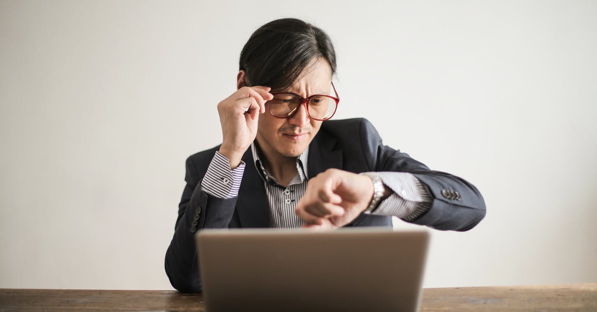 How do I check the time remaining in a song without enabling Advanced HUD? - Young frowning man in suit and glasses looking at wristwatch while waiting for appointment sitting at desk with laptop