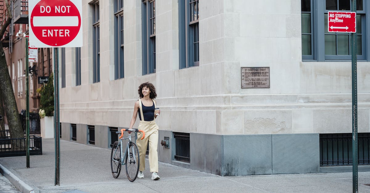 How do I control Nana? - Contemplative ethnic woman with coffee and bike walking on pavement