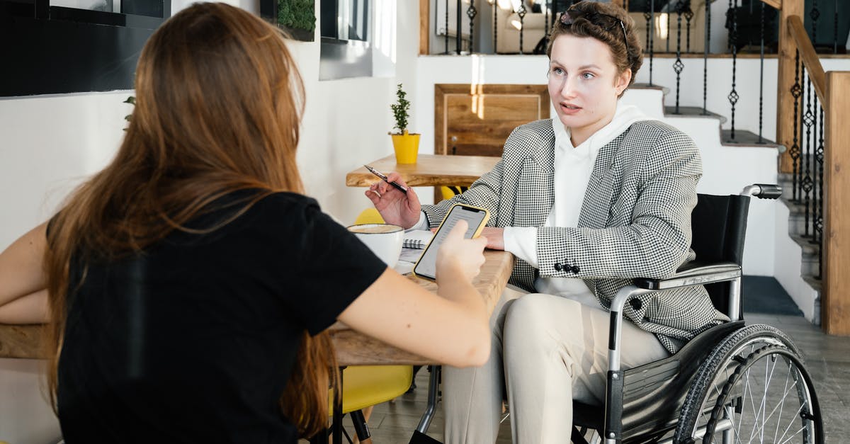 How do I disable chat? - Concentrated female using wheelchair talking to coworker during coffee break in modern cafeteria