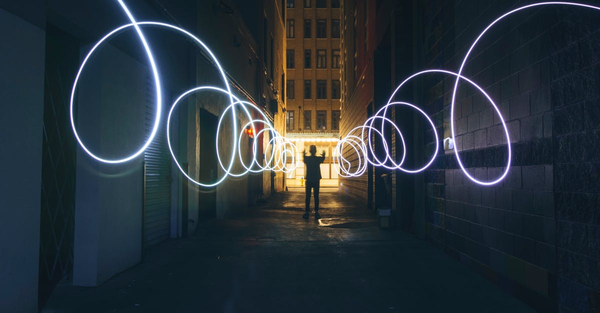 How do I disable the dynamic contrast (aka auto exposure)? - Long exposure full body person silhouette making circles with bright flashlight while standing on narrow dark city street between tall urban buildings