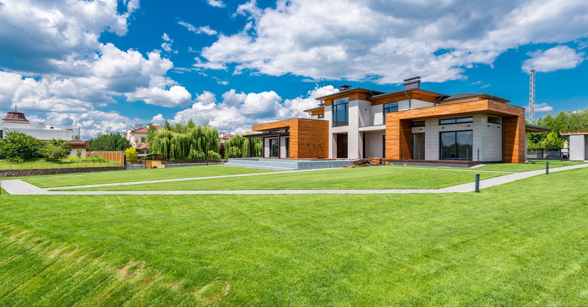 How do I enable Silent Mode? - Exterior of modern residential house with wooden walls and green grass growing in yard against blue sky with white clouds