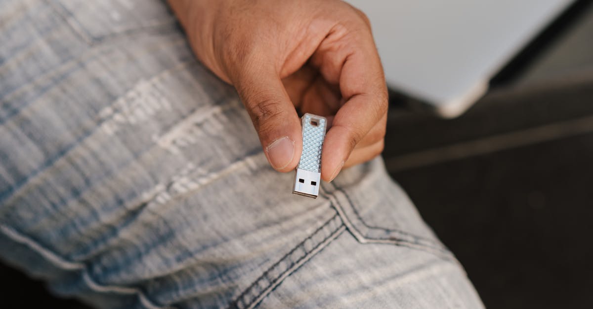 How do I erase Save data on Pokemon White? - From above of crop anonymous male in jeans demonstrating flash drive while sitting near laptop