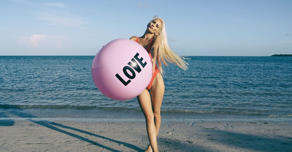 How do I get the Love Balls? - Woman Wearing Orange Swimsuit While Holding Pink Inflatable Beside Body of Water