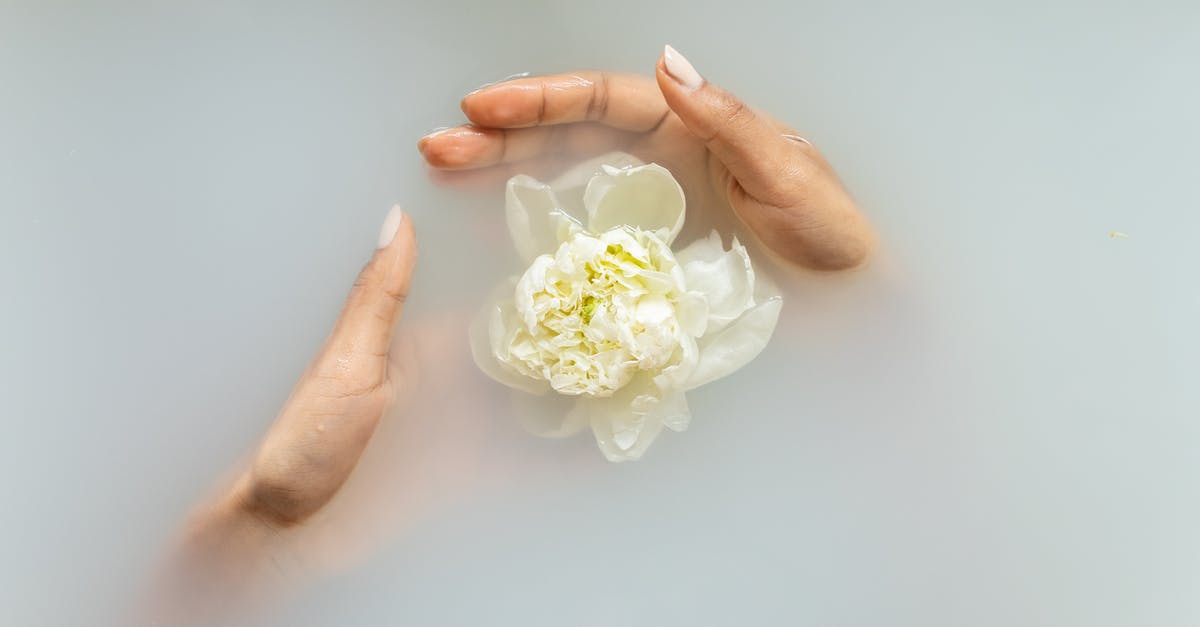 How do I heal as Ed the Undying? - Unrecognizable female with manicured hands holding white flower in hands in soapy water during spa procedures