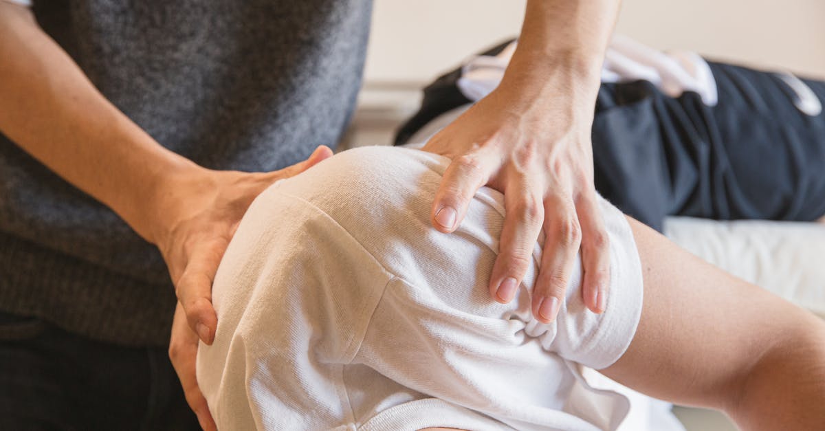 How do I heal Batfellow? - Crop anonymous medical specialist rubbing shoulders of male client lying on couch in medical salon