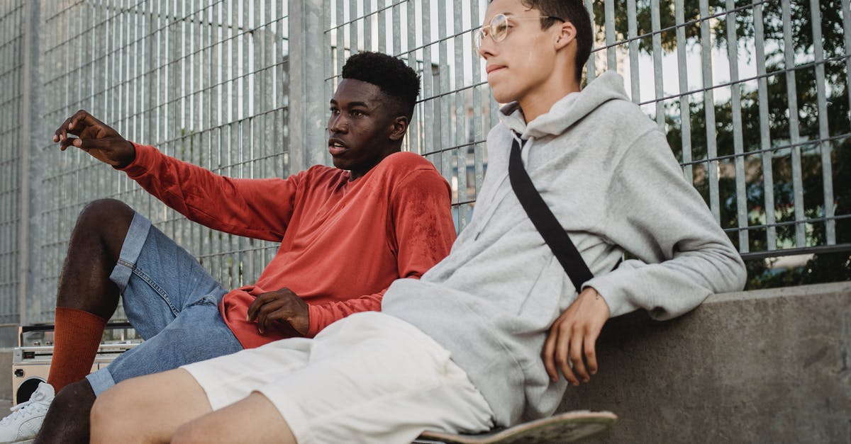 How do I keep my fences from breaking? - Serious multiracial young men talking to each other while sitting on skateboards in city park