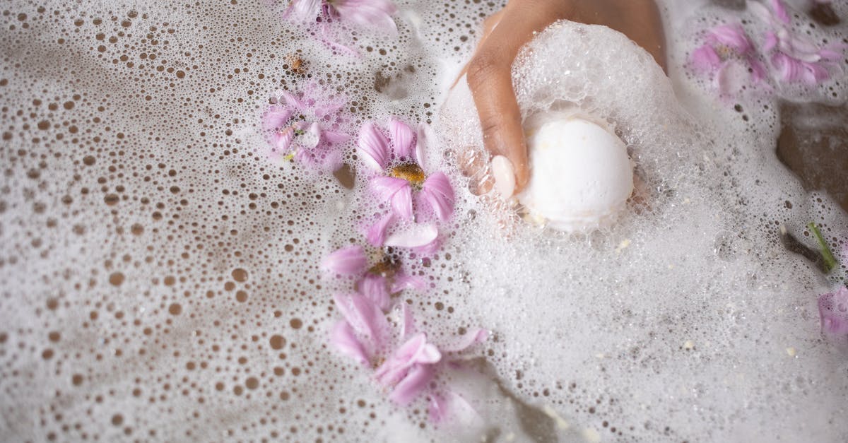 How do I know if water is fresh or salt? - Woman holding ball of bath salt in water with foam and flowers