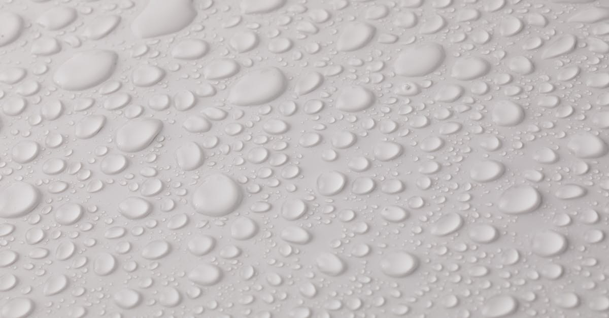 How do I lower the water even more? - Closeup top view of plain wet abstract surface with small dripped water drops of different shapes placed on white background