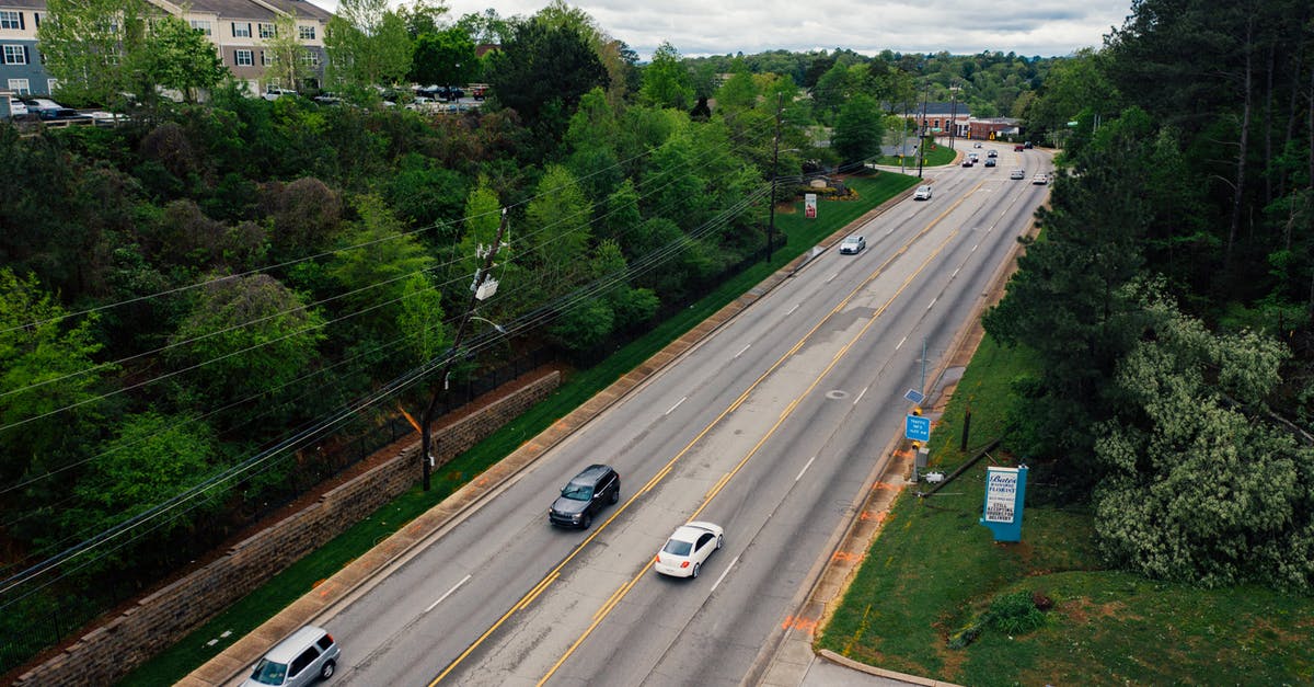 How do I move from settlement to settlement to another? - From above modern cars driving along asphalt road surrounded with green trees in suburb area