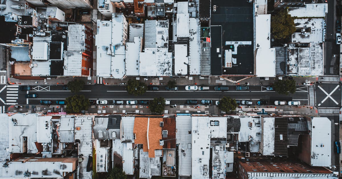 How do I move from settlement to settlement to another? - Aerial view of cars moving on city street surrounded by houses with white roofs in residential district