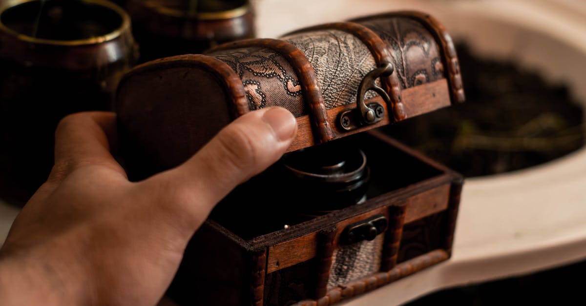 How do I open a chest? - Crop anonymous male artisan opening small antique wooden chest placed on table at home