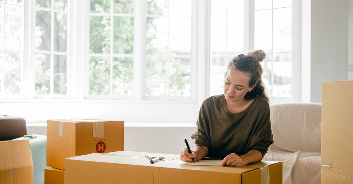 How do I open the new dreamy content in Candy Crush? - Content lady in casual clothes writing with pen on cardboard box while sitting near window in daylight in apartment preparing to relocate