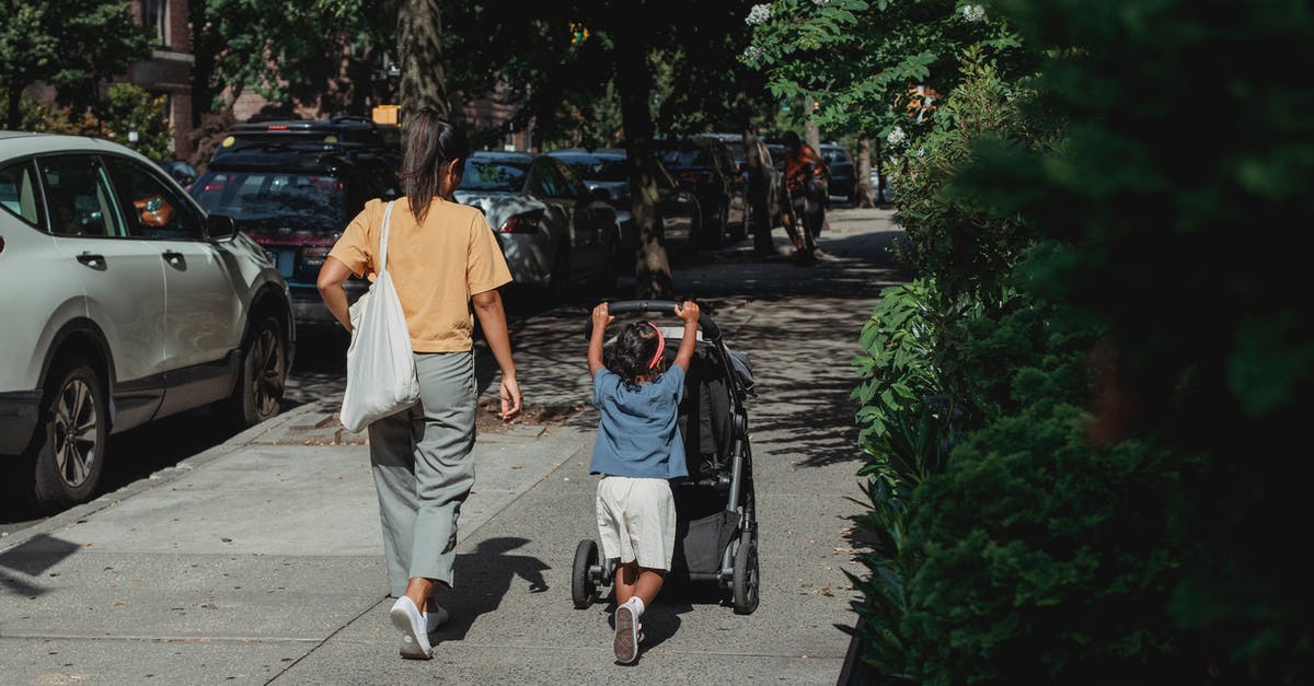 How do I roll back versions? - Full body back view of anonymous ethnic woman with bag walking on sidewalk near girl pushing baby stroller on sunny street