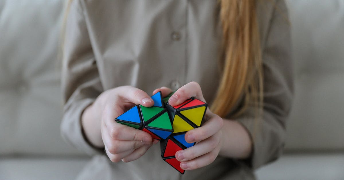 How do I solve Question 42, Level 5 in Think Different? - Crop anonymous girl demonstrating and solving colorful puzzle with triangles in soft focus