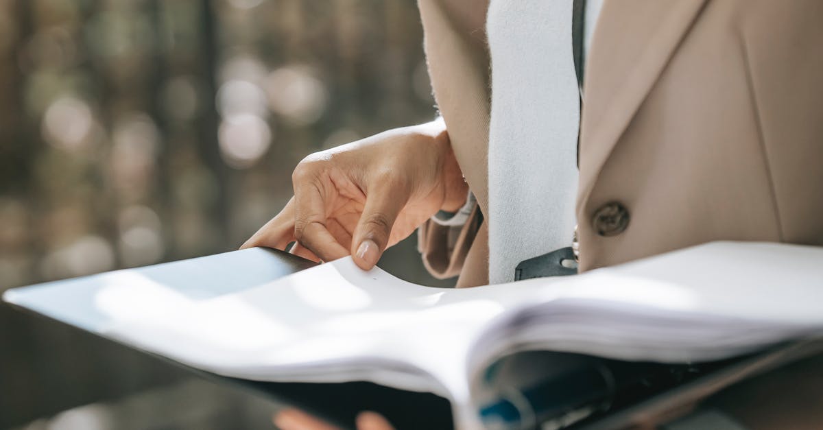 How do I turn on the camera? - Crop faceless female entrepreneur in stylish jacket reading important documents in black folder